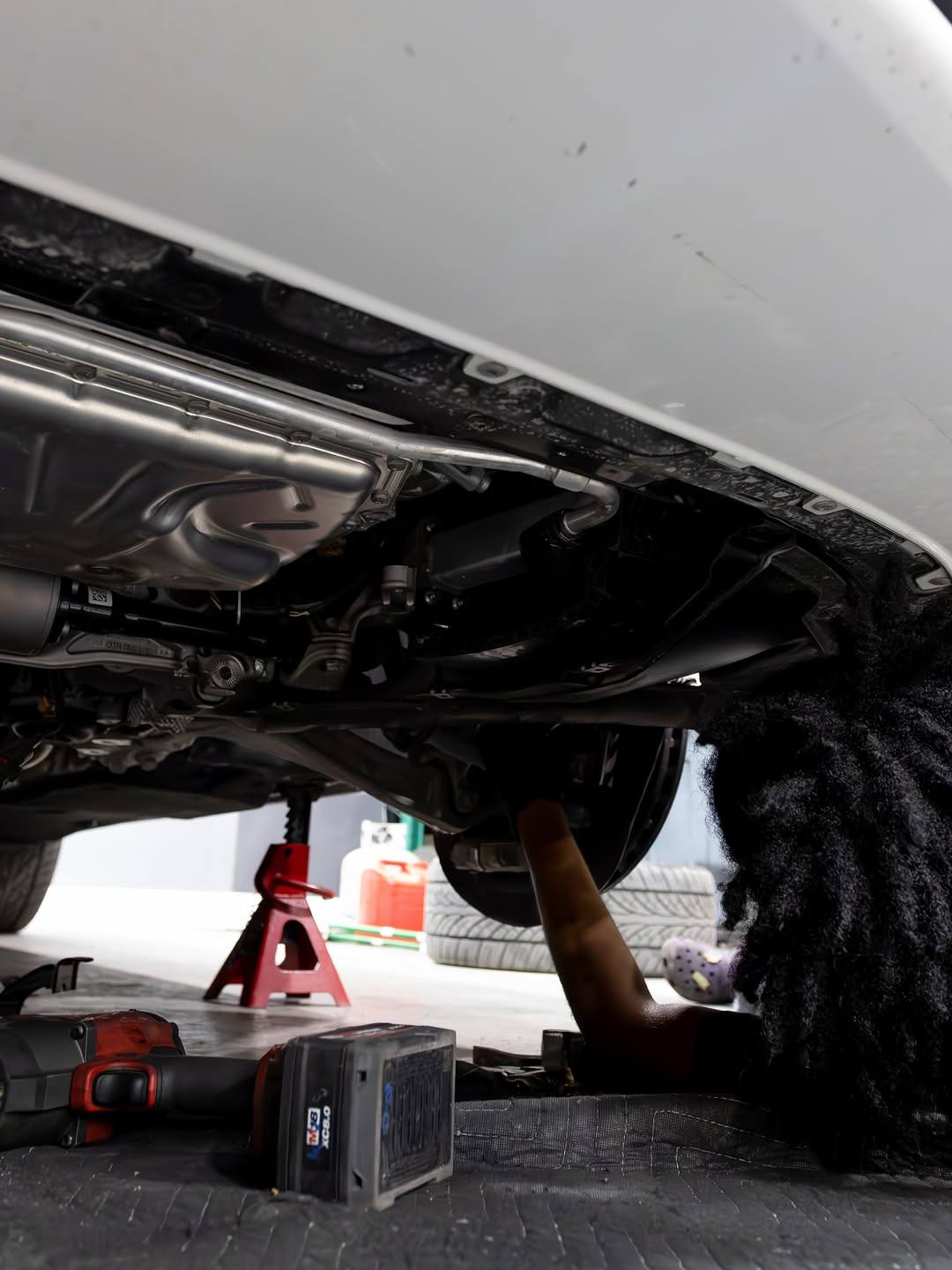 Technician working under a white Lamborghini Urus